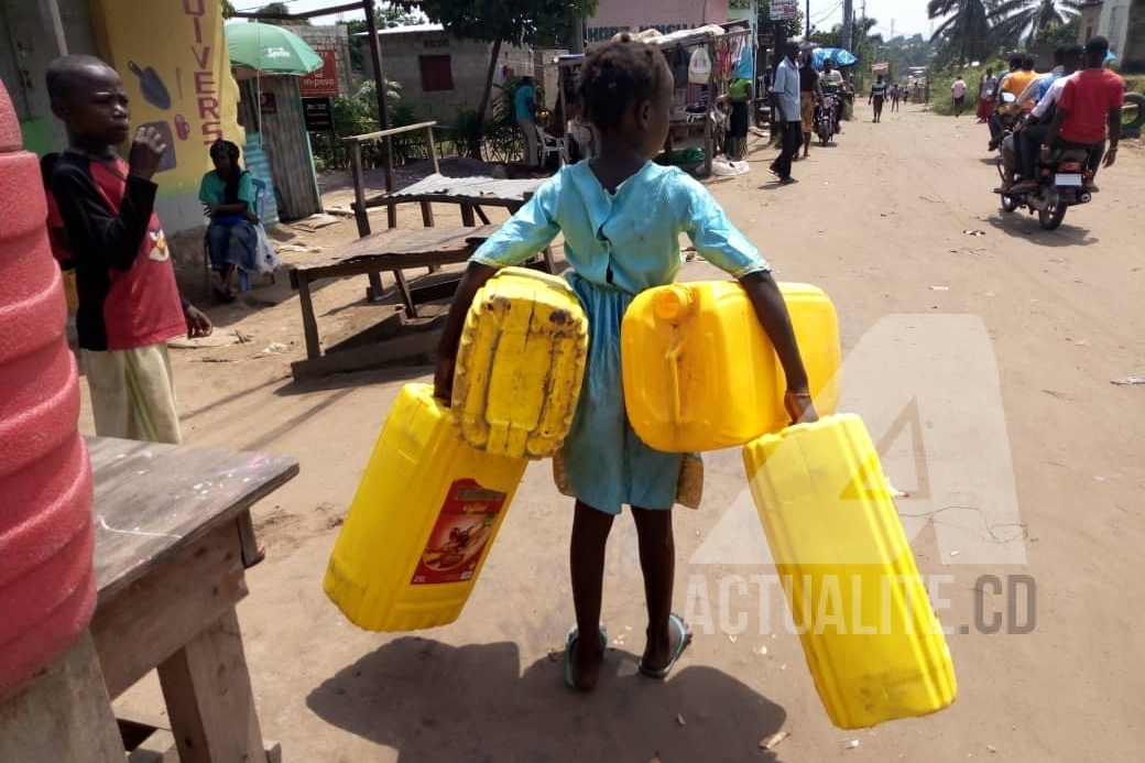  Dorcas, fillette de 7ans avec ses quatre bidons de 25 litres.