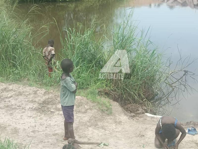 Trois enfants au bord de la rivière N'djili se livrant à la pêche 